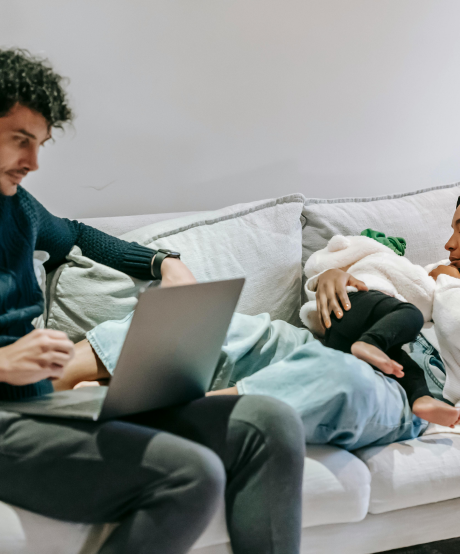 New parents sitting on couch while mother feeds baby