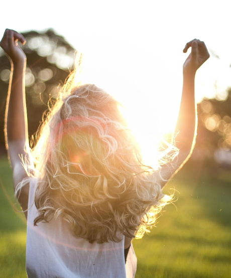 Women walking outside with her hands in the air taking in the sunrise